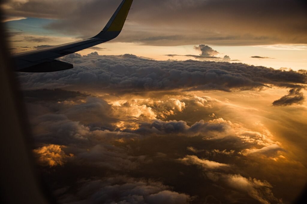 View from an airplane window over clouds at sunset