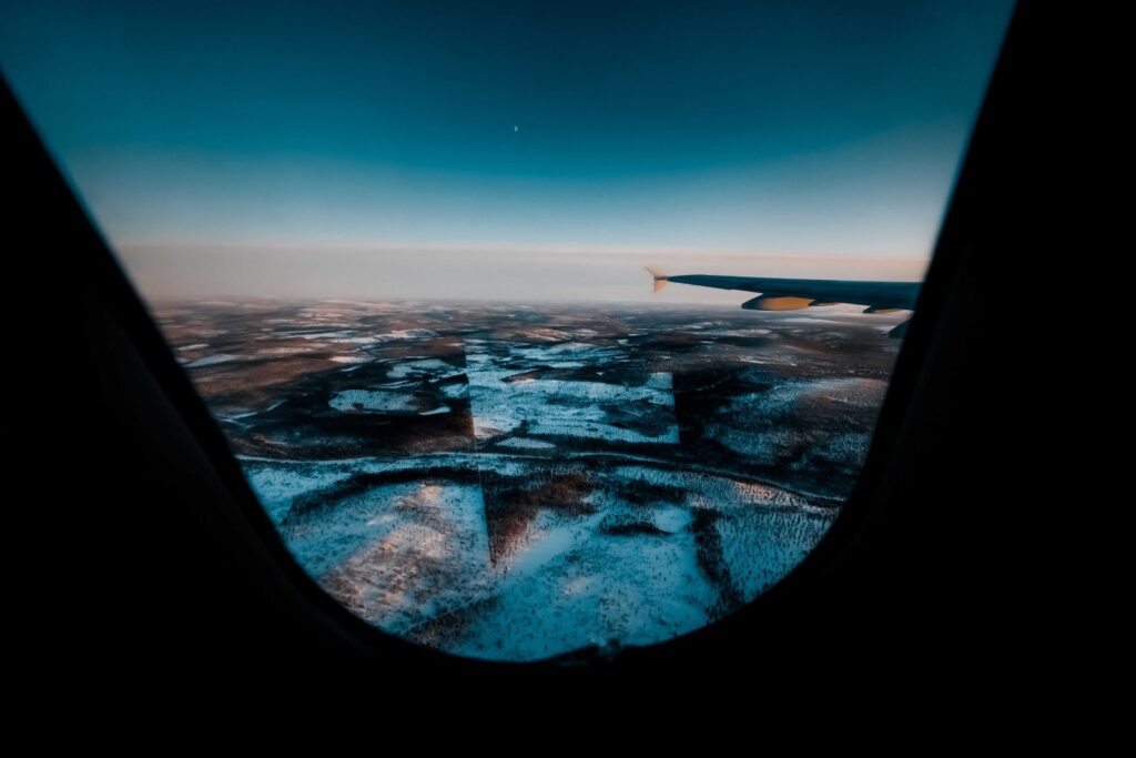 Airplane window view over snowy landscape at dawn